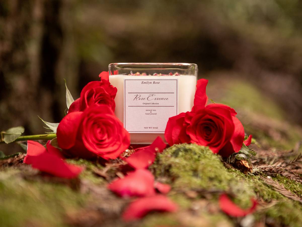 Stack of valentine paper plates nearby on a rustic wooden table with rose petals and candles