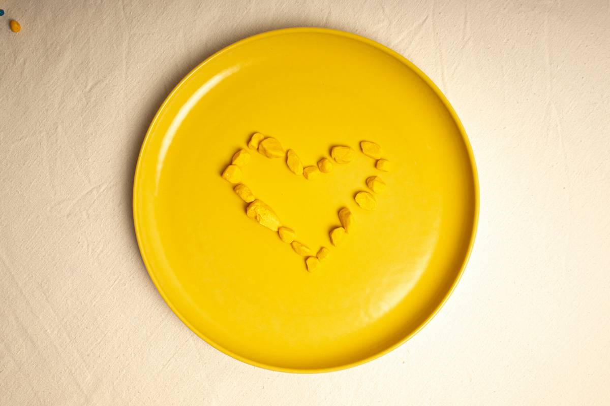 Assorted valentine paper plates styled with roses, chocolates, and candles on a rustic wooden table